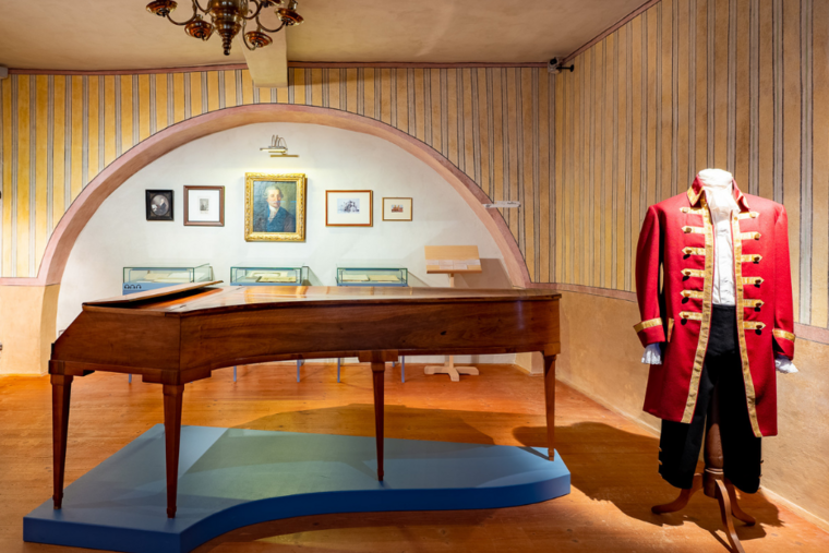 Ausstellungsraum mit Klavier und historischer Kleidung 