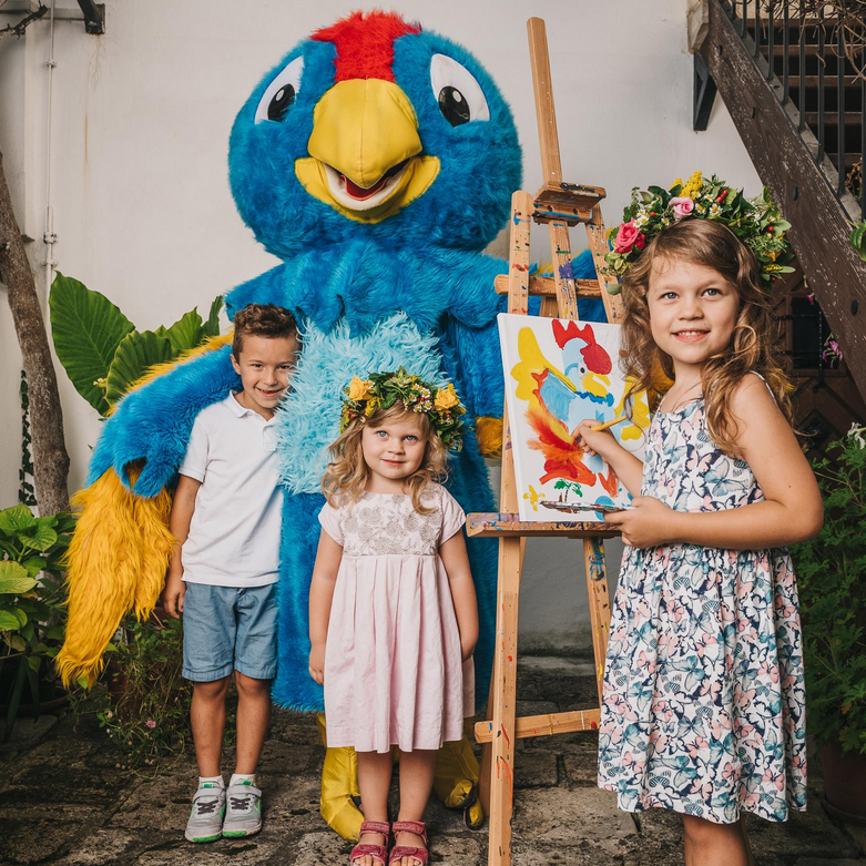 drei Kinder mit Maskottchen Pauli Plappagei